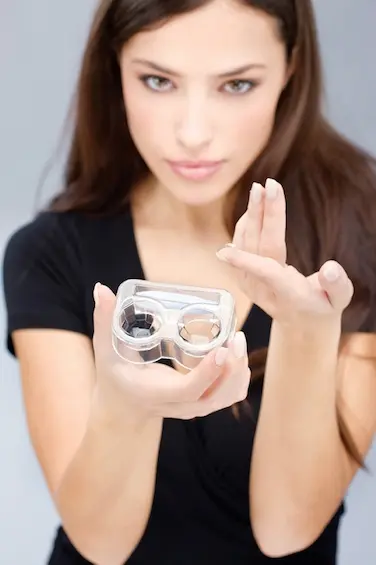 A woman showing a contact lens and case