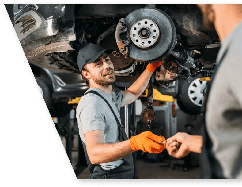 mechanic handing a tool to another mechanic repairing a car