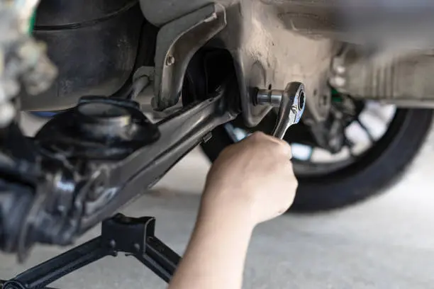 Close up wrench in hand a man adjust and lock bolt in car body in service concept of Suspension system
