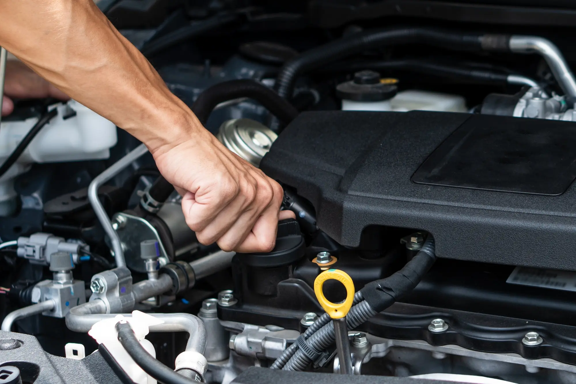 Hand of car machanic checking oil and oil change in car engine and car maintenance in garage.