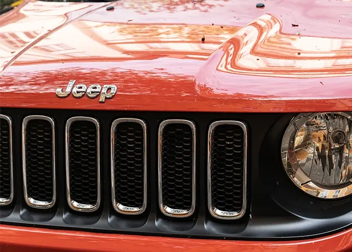 The front view of an orange Jeep vehicle, showcasing its distinctive grille and headlights.
