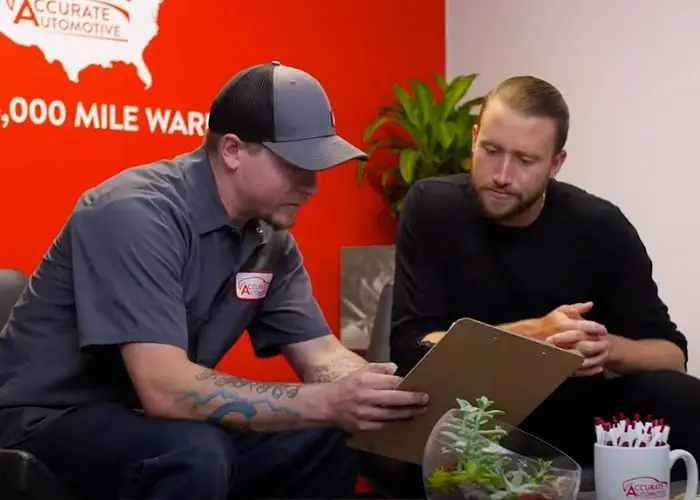 a person looking at a clipboard discussing maintenance with another person in the background