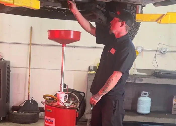 A technician is performing an oil change on a car