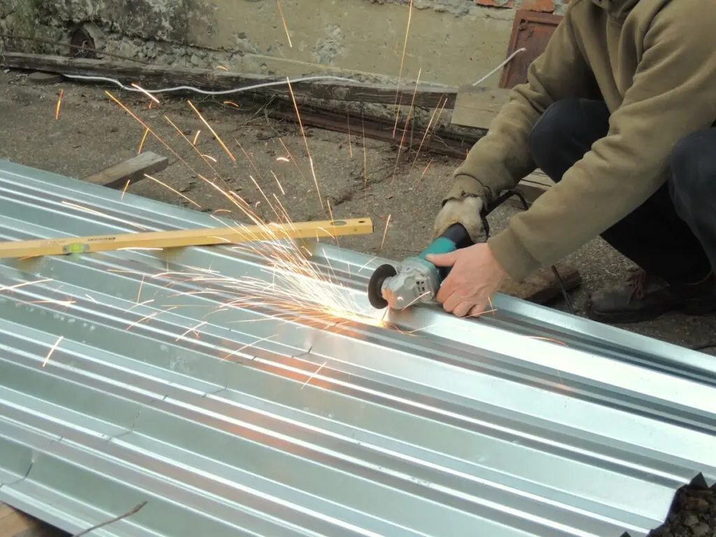 man using a small saw to cut corrugated metal roofing panels