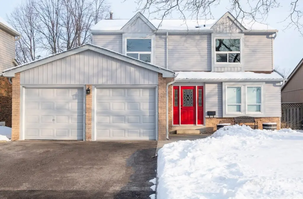 Typical Suburban Detached House with Grey Siding and Red Door After Snow. how to install vinyl siding