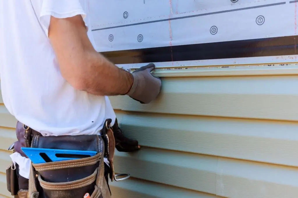 siding companies raleigh nc worker installing and repairing new cream siding family house