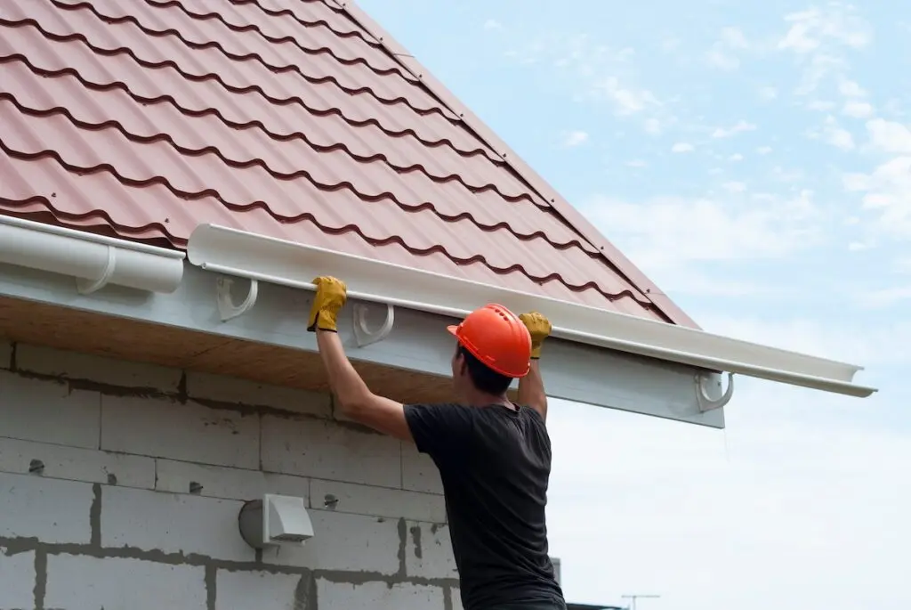 worker installs the gutter system on the roof