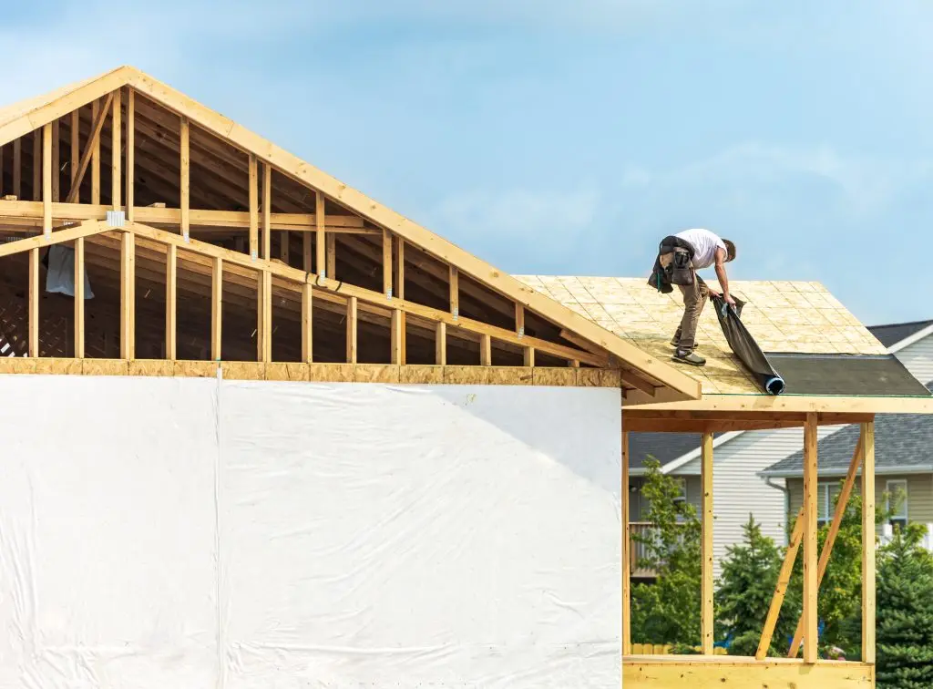 where does ice and water shield go on a roof Worker installing underlayment sheet on wooden roof of new house. Renovation, improvement for exterior residential by professional builder. Durable build and construction business. Labor job concept