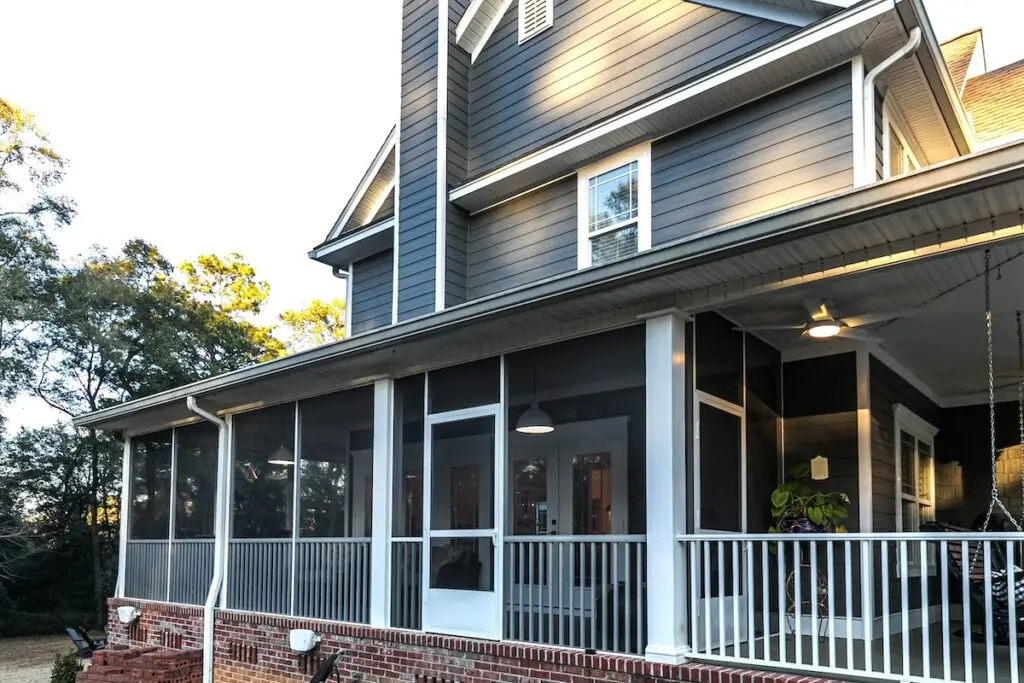 Side view of a large two story blue gray house with wood and vinyl siding. how to install vinyl siding
