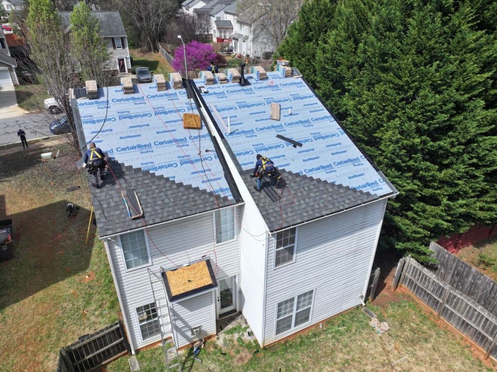 workers on top of shingles roof
