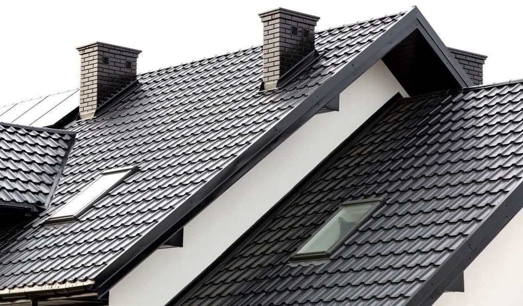 what are the most durable roofing materials? Roof of a new home. Ceramic chimney, metal roof tiles, gutters, roof window. TV antennas attached to the chimney. Single family house.