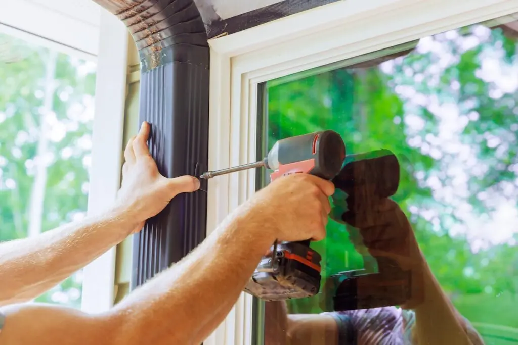 Handyman is assembling gutter channel that is attached to roof with a installation of gutter