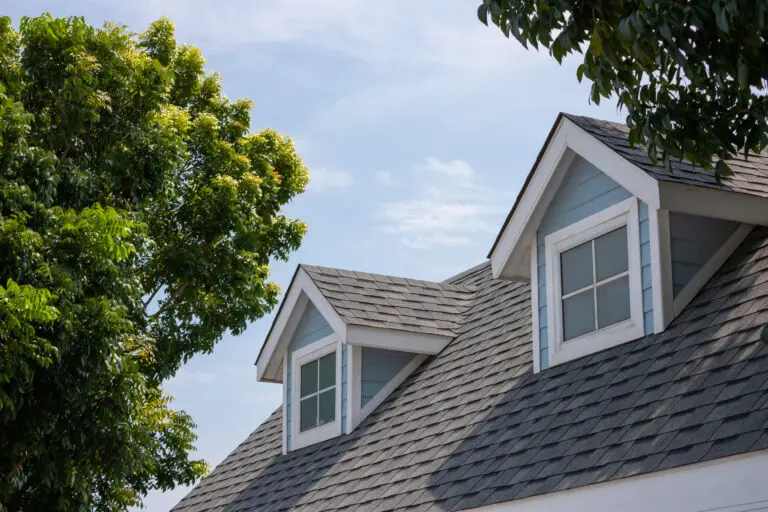 Roof shingles with garret house on top of the house among a lot of trees.