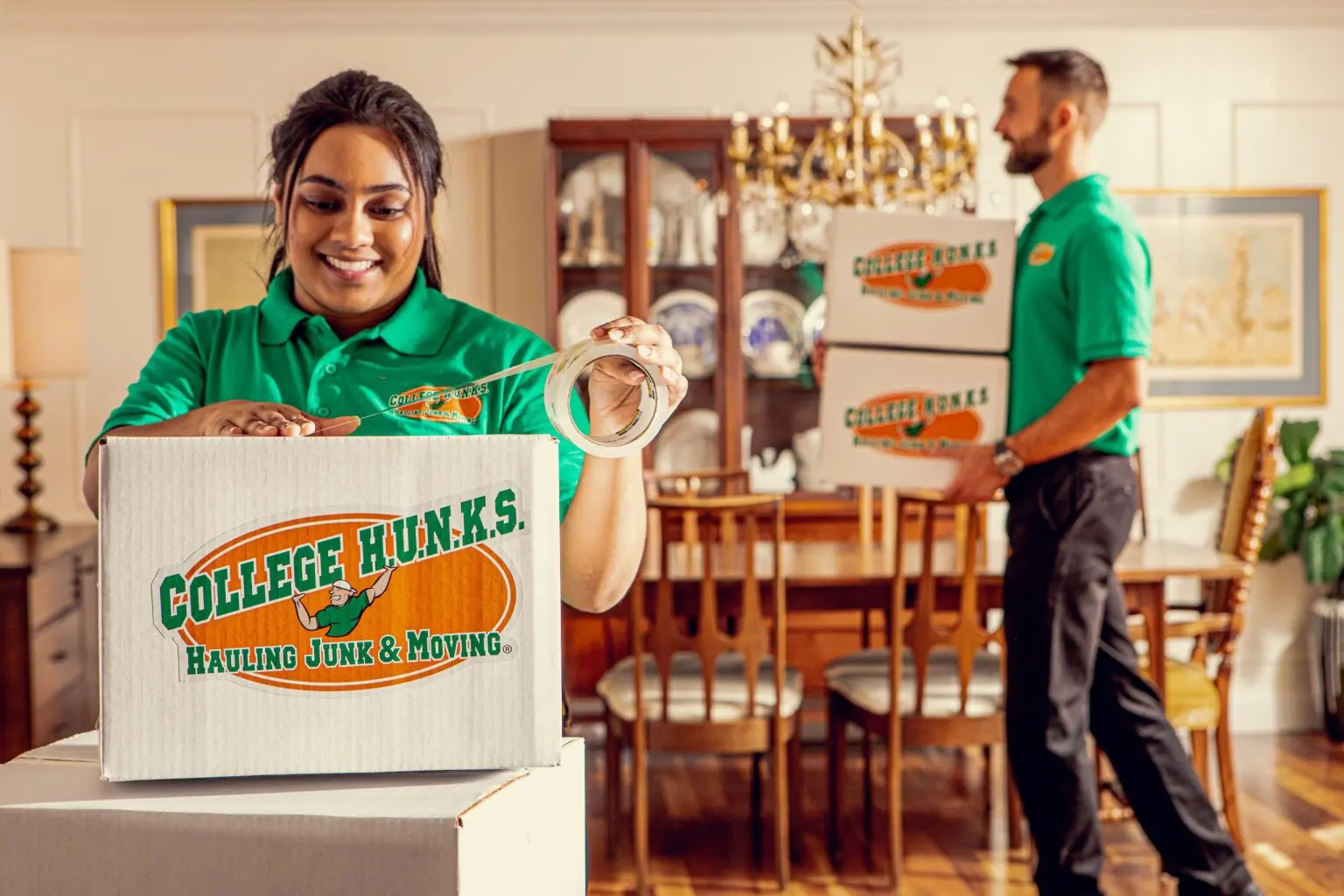 Uniformed College HUNKS crew members packing branded boxes in a home, the per zone labor a franchise owner budgets for
