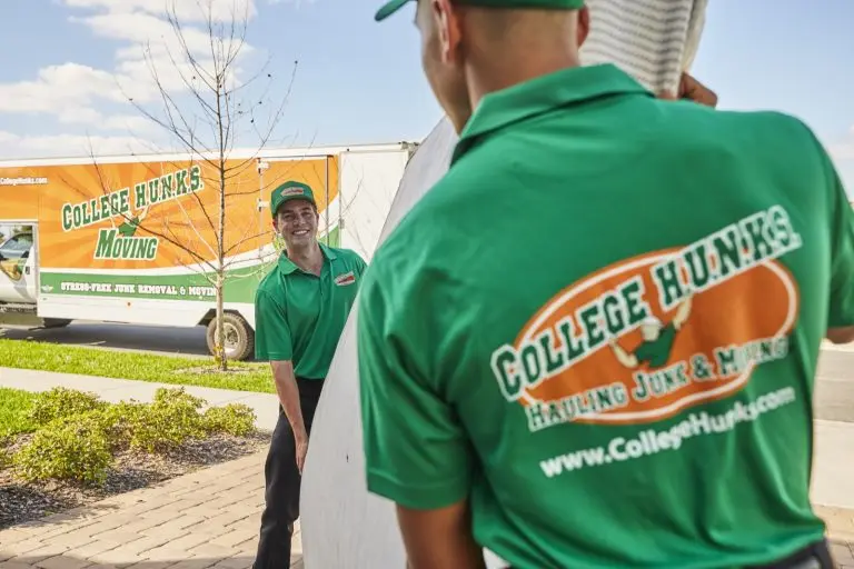 College HUNKS movers carrying furniture to a branded moving truck at a residential job