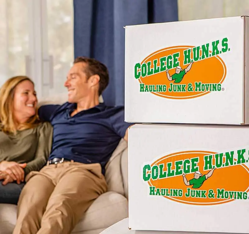 Customers relaxing beside College HUNKS branded moving boxes after a completed home service job