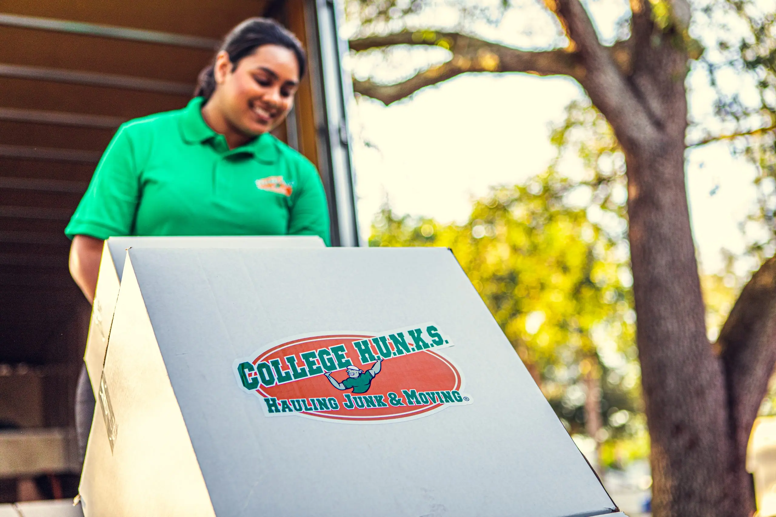 College HUNKS mover carrying a branded moving box from the truck