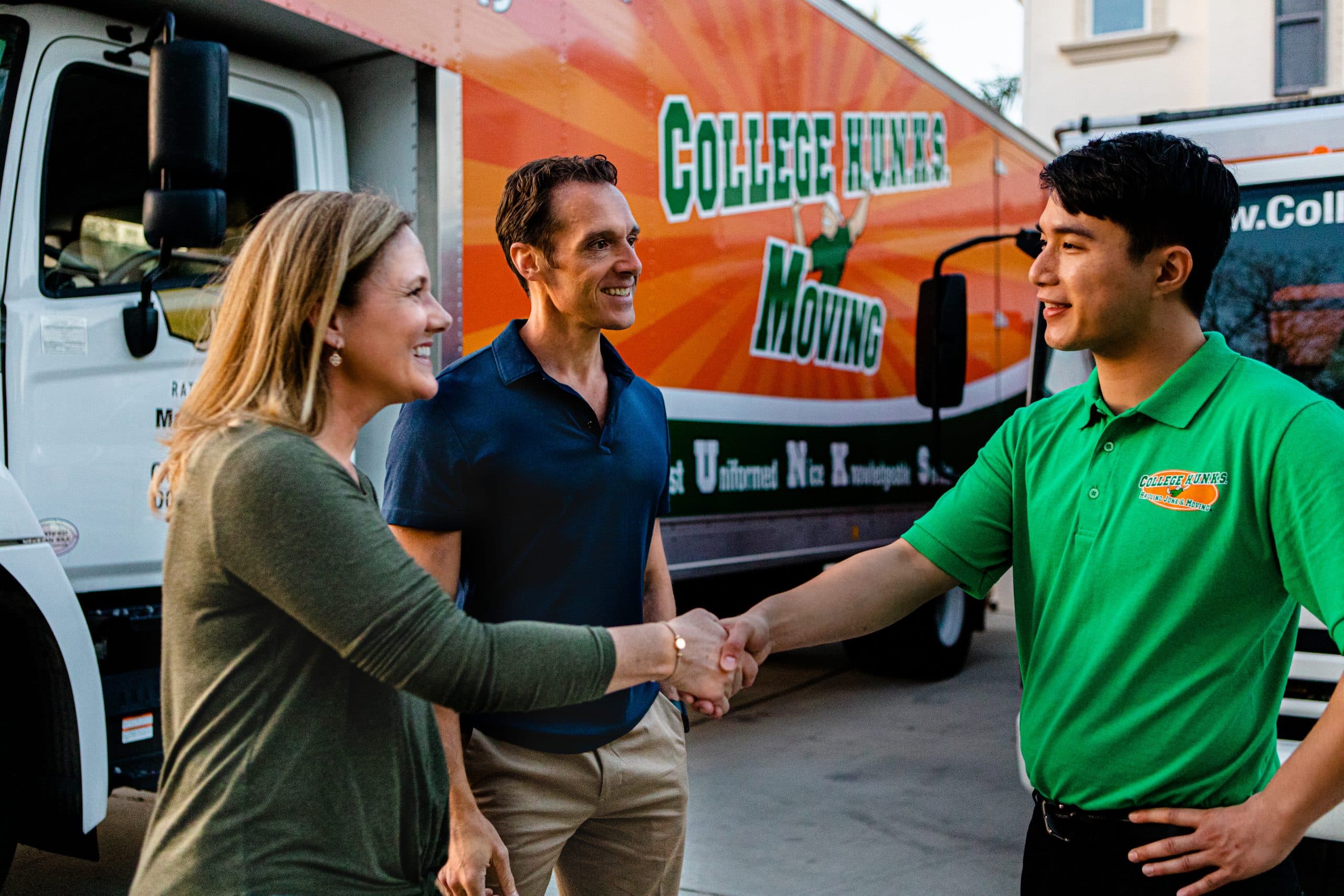 Couple shaking hands with a College HUNKS team member beside a branded moving truck