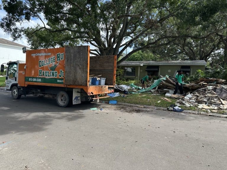 College HUNKS junk removal truck and crew clearing a large debris pile at a job site