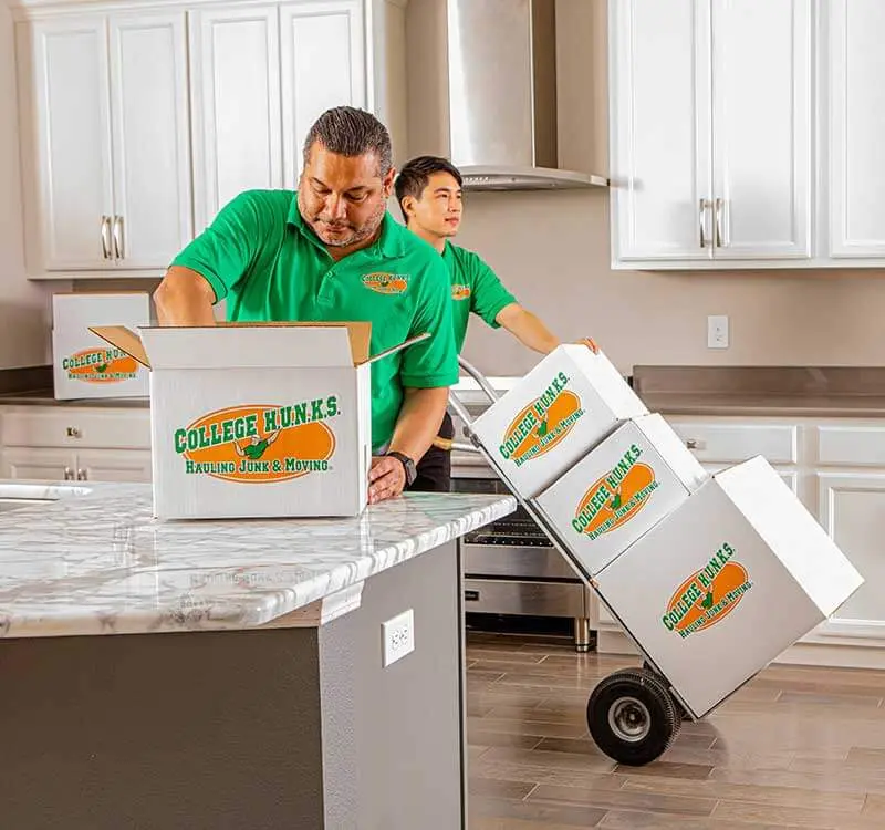 Uniformed crew loading boxed household items, the labor cost line inside every junk removal price