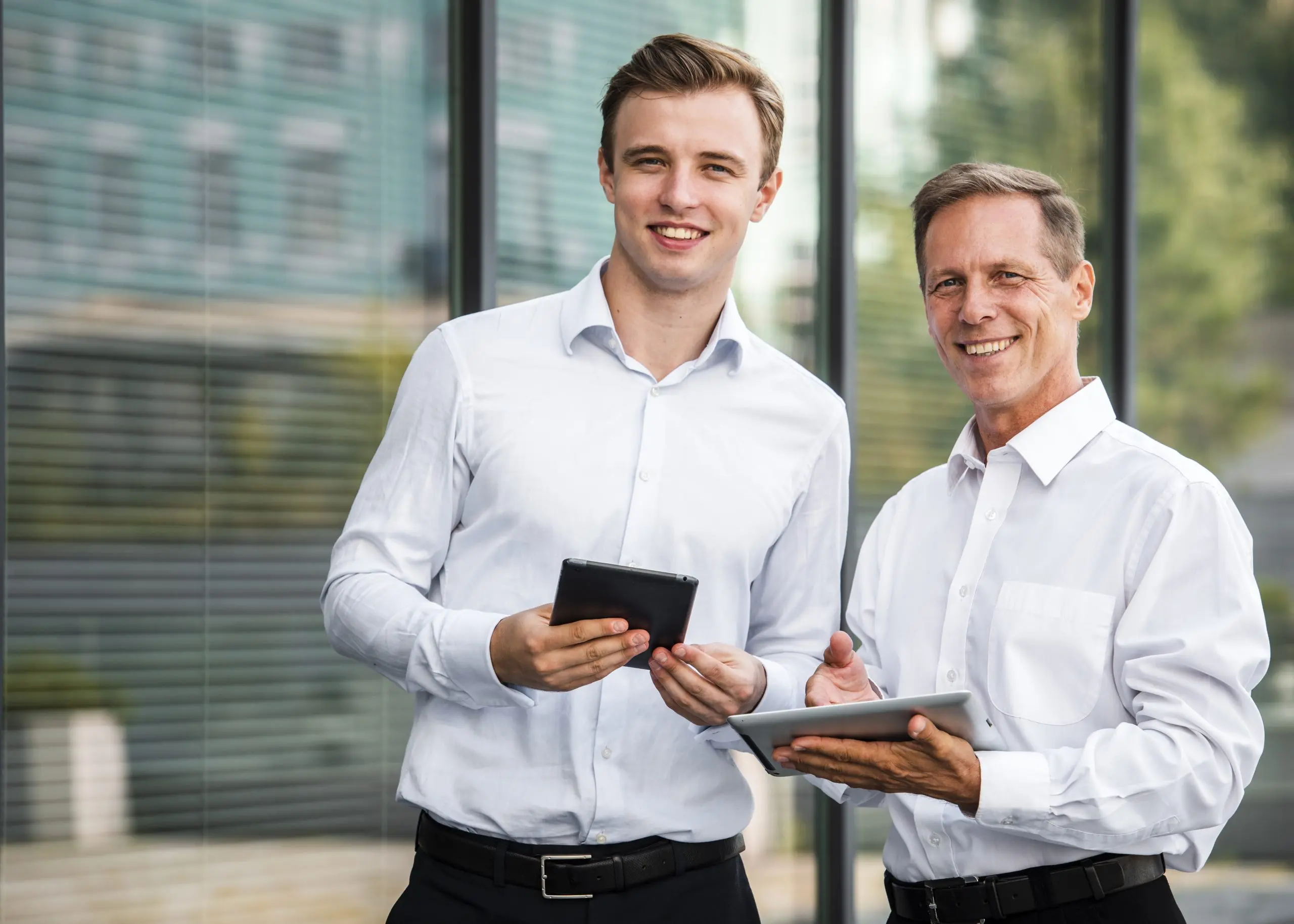 An experienced manager and a younger colleague reviewing plans on tablets while weighing self-employment ideas after 50