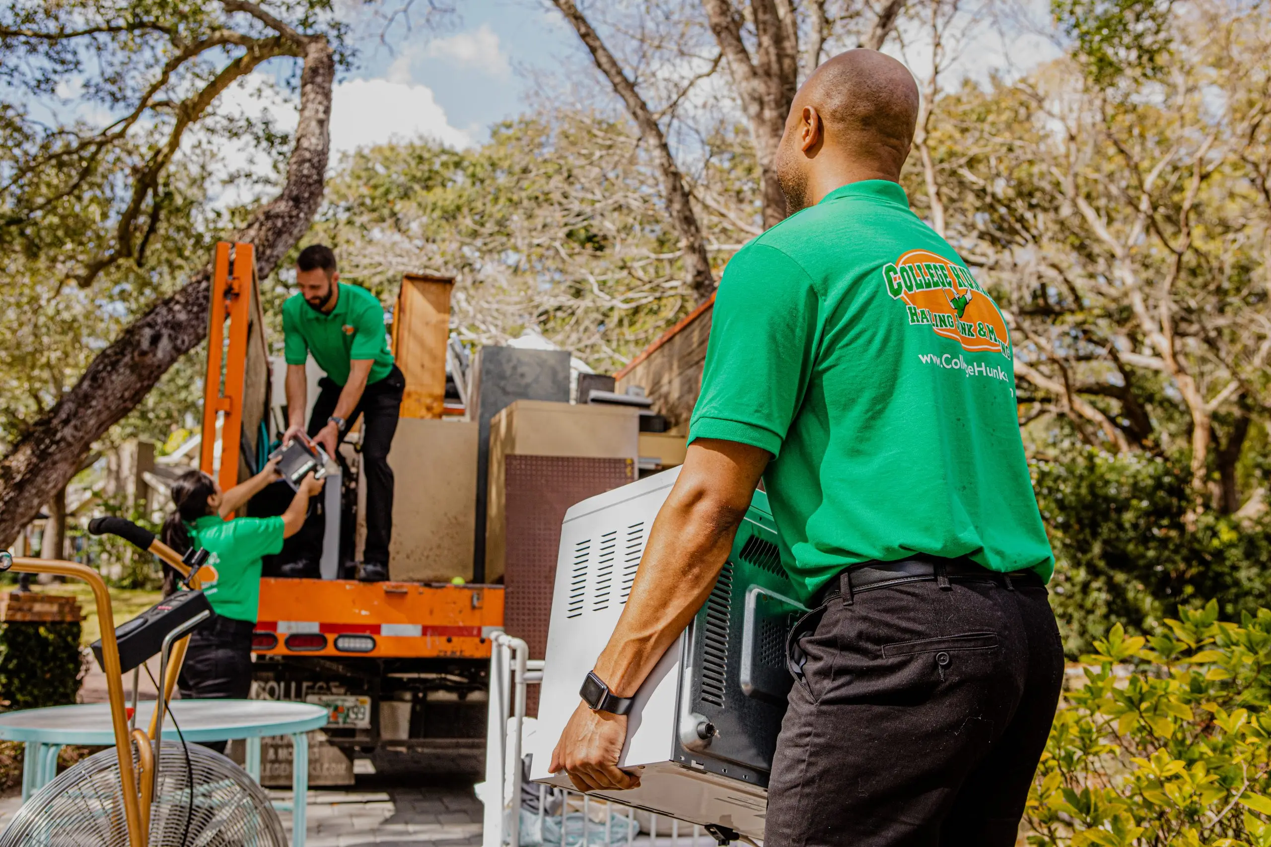 College HUNKS crew loading furniture and appliances into a junk removal truck