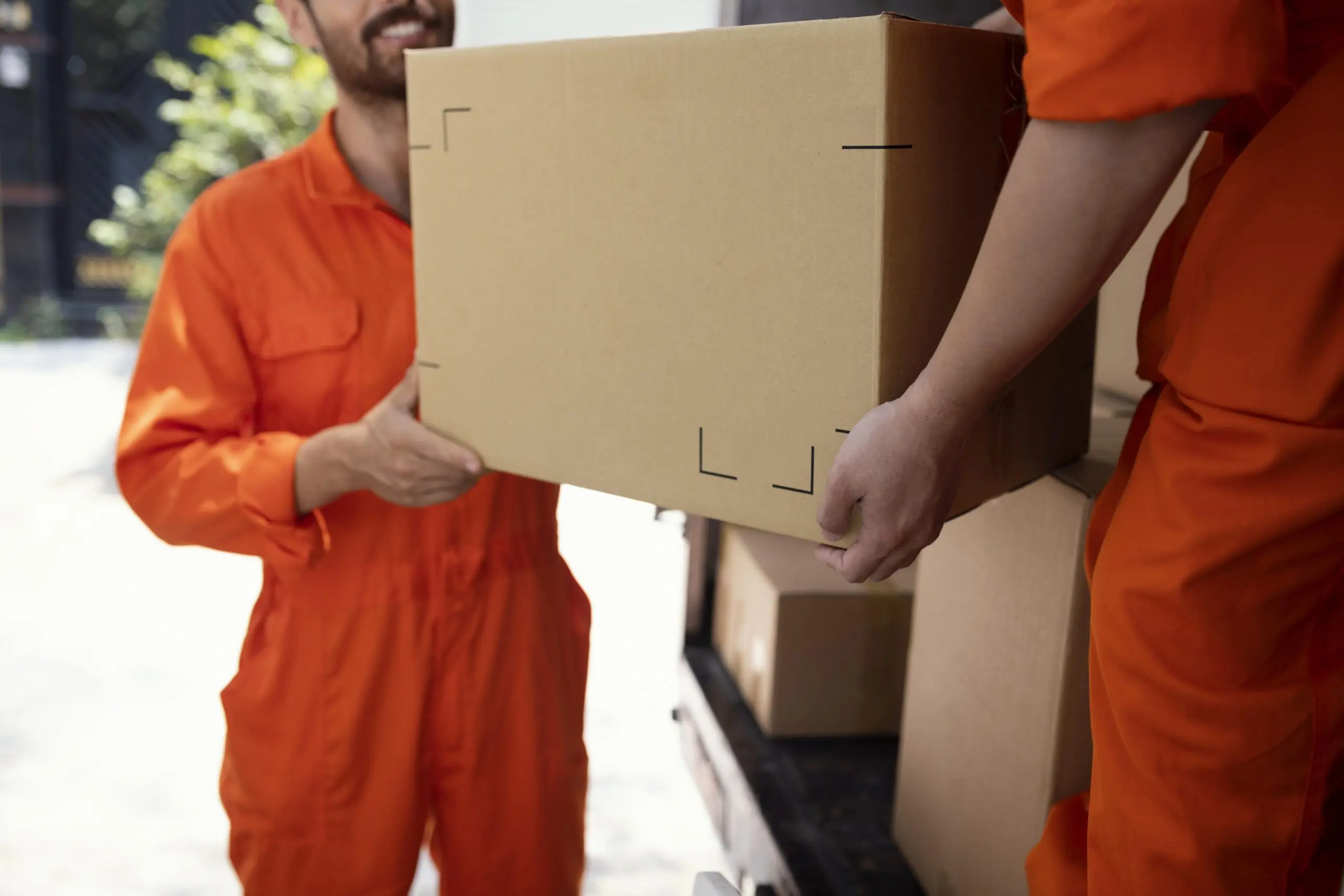 Two uniformed movers loading a packed box onto a truck, the booked work that lets a financed franchise owner cover payments