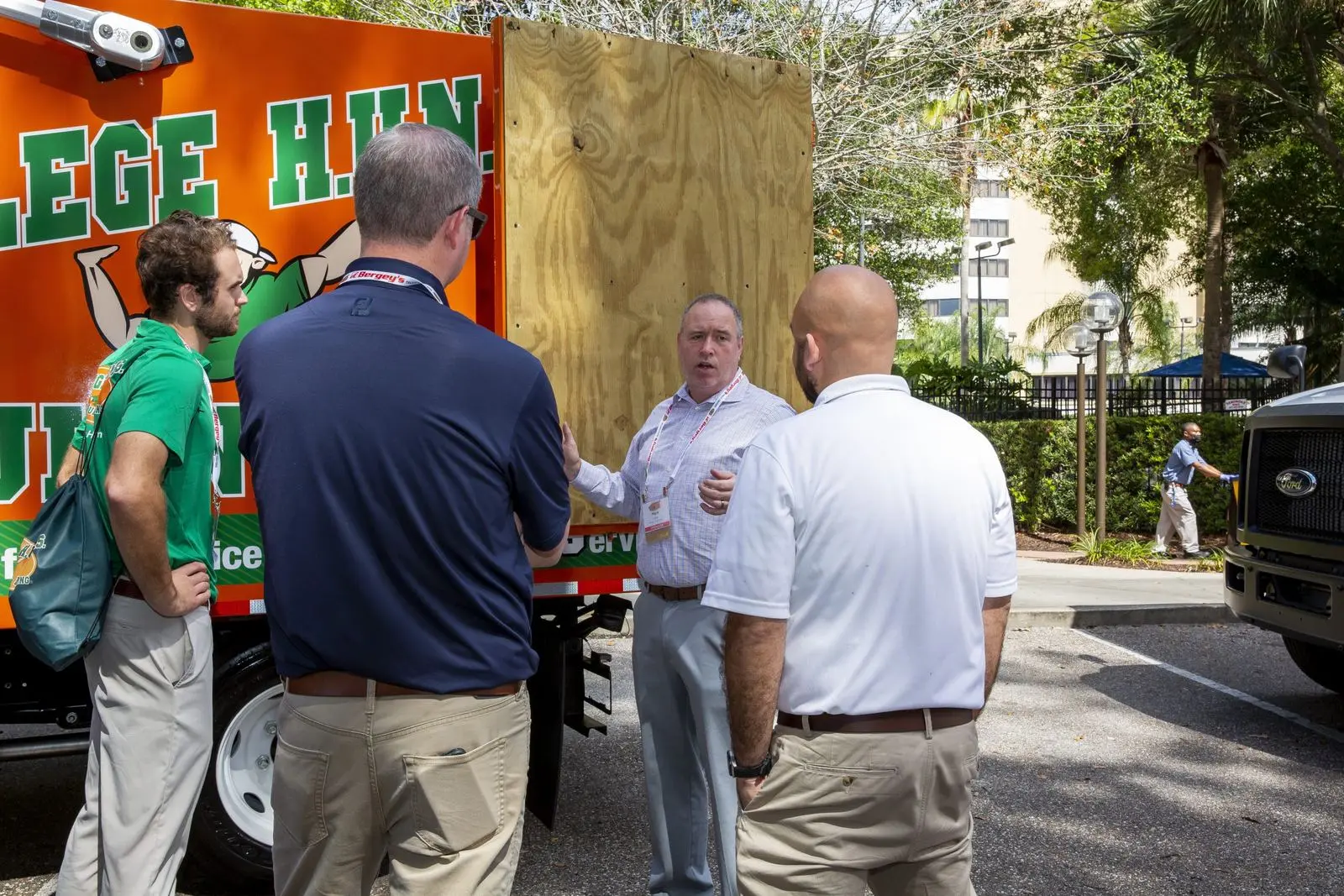 Experienced professionals talking beside a College HUNKS truck, weighing business ownership after being laid off at 60