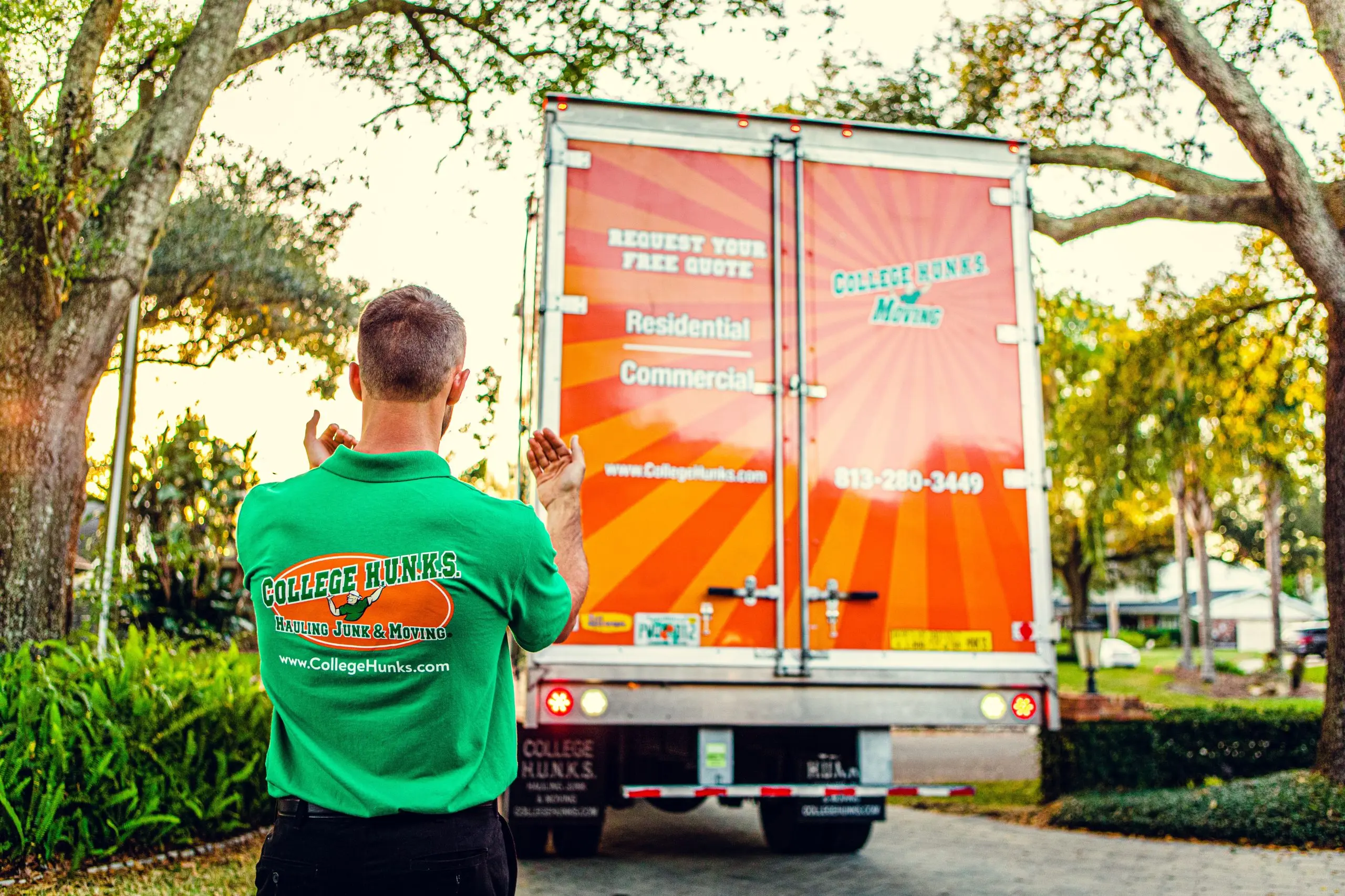 College HUNKS crew member at the back of a branded truck whose door doubles as rolling advertising
