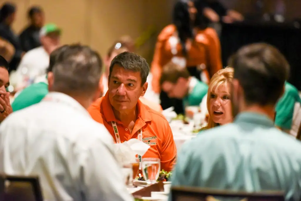College HUNKS franchise owners in branded polos talking together at the brand's annual owner reunion