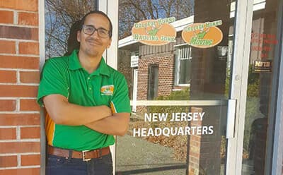 College HUNKS franchise owner in a green polo standing beside the New Jersey headquarters door