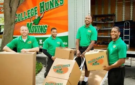 College HUNKS team members in green uniforms loading boxes by a branded truck