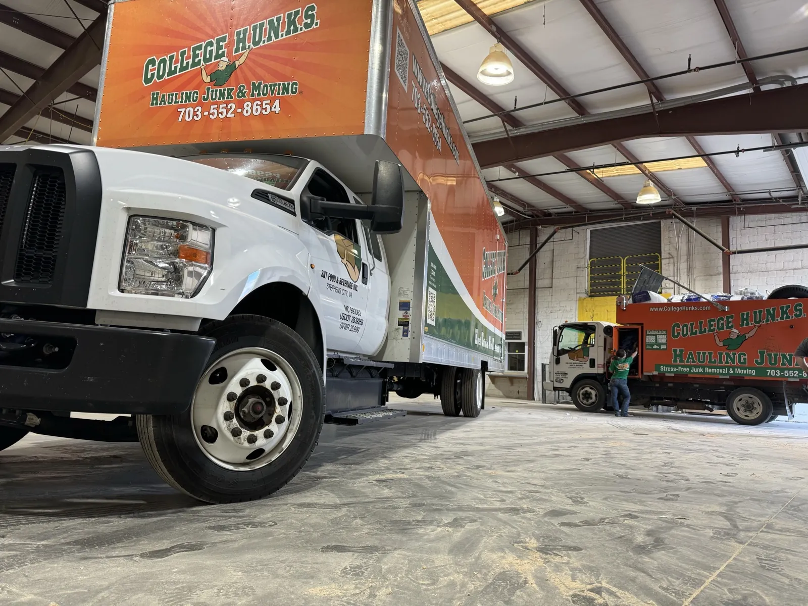 College HUNKS junk and moving trucks in a franchise warehouse, the operation behind a junk removal franchise investment