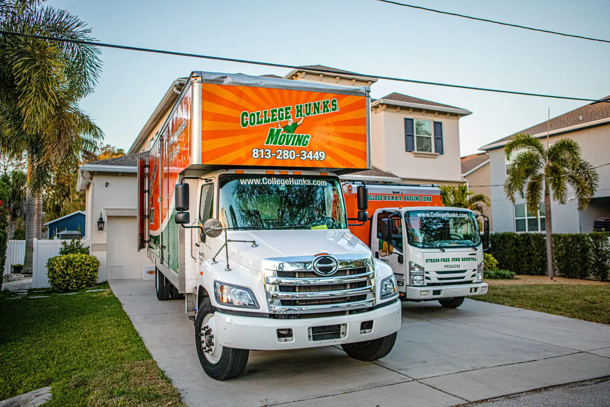 College Hunks Hauling Junk and Moving trucks parked in a driveway, showing the two-in-one franchise model