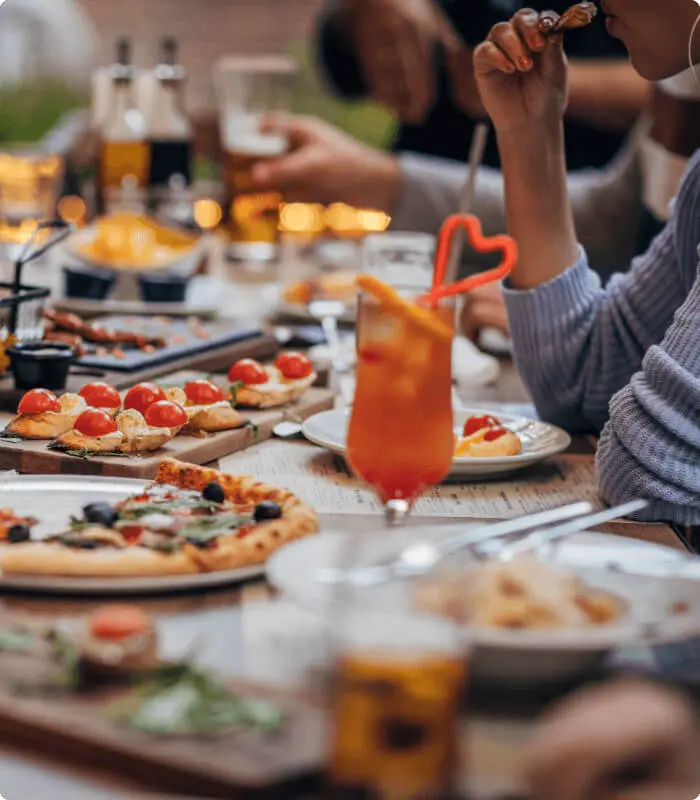 Guests enjoy pizza, appetizers, and cocktails at Village Clubs Camelback, in a lively and festive dining atmosphere.