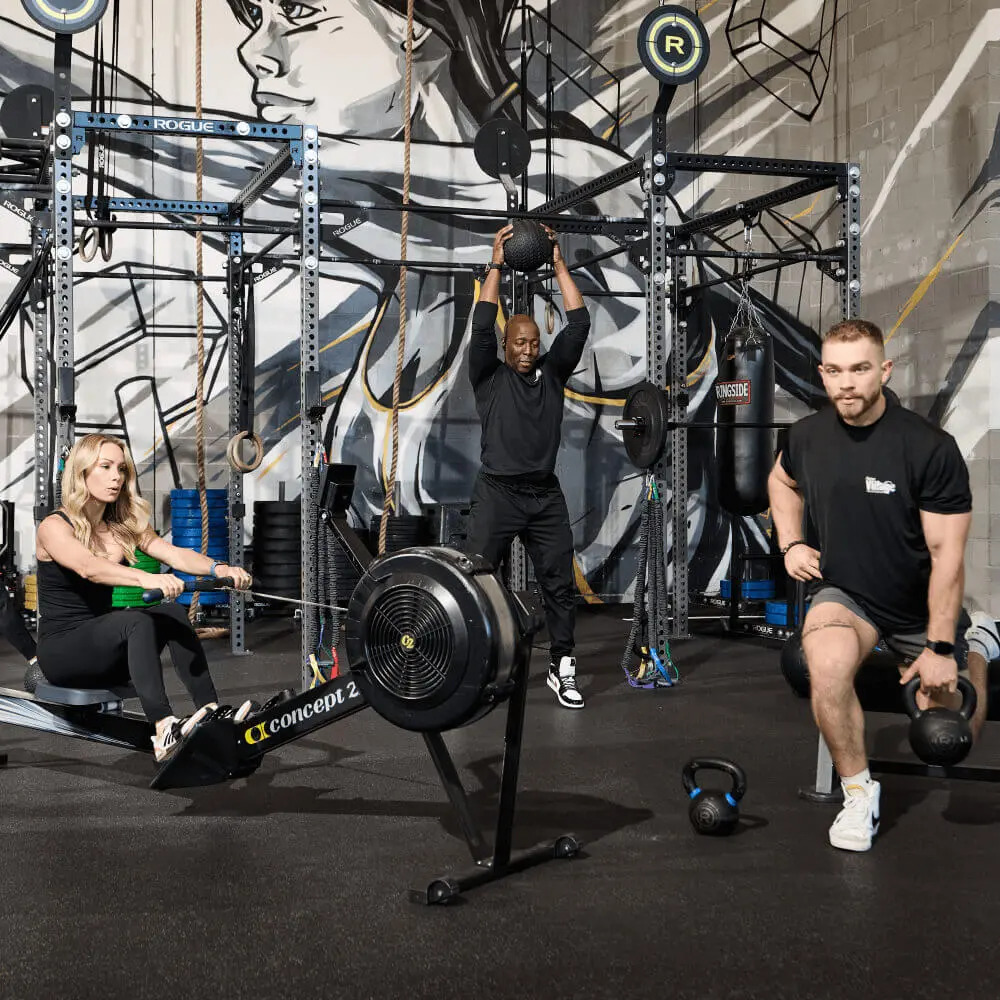 Members exercise at Village Clubs Camelback: rowing, medicine ball lifts, and kettlebell lunges with gym equipment in view.