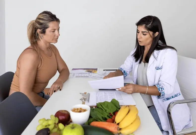 A Village Clubs nutritionist at Camelback reviews membership benefits with a client, fresh produce and nuts on the desk in front.