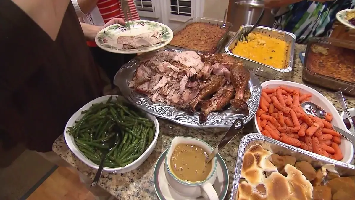 Village Clubs at Camelback holiday table with Thanksgiving dishes; person holding a plate ready to serve.