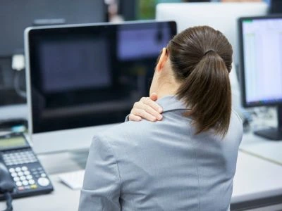 woman holding the back of her neck while experiencing neck pain and stiffness
