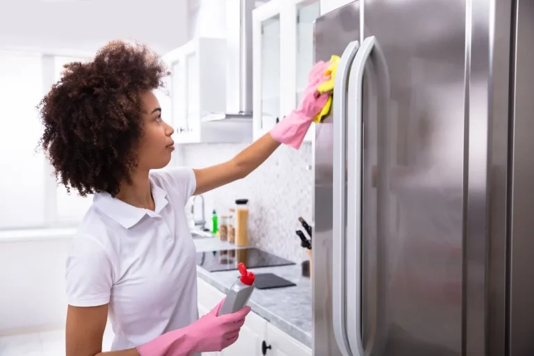 House cleaner cleaning outside of refrigerator