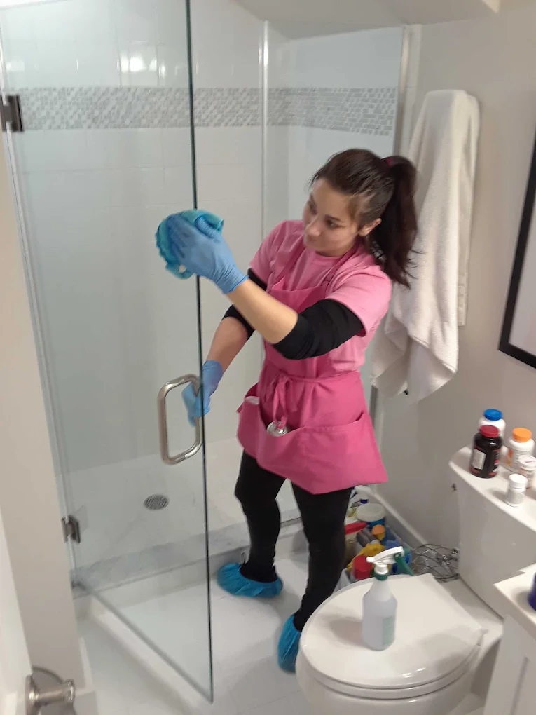 Maid cleaning shower door in Palm Beach County home