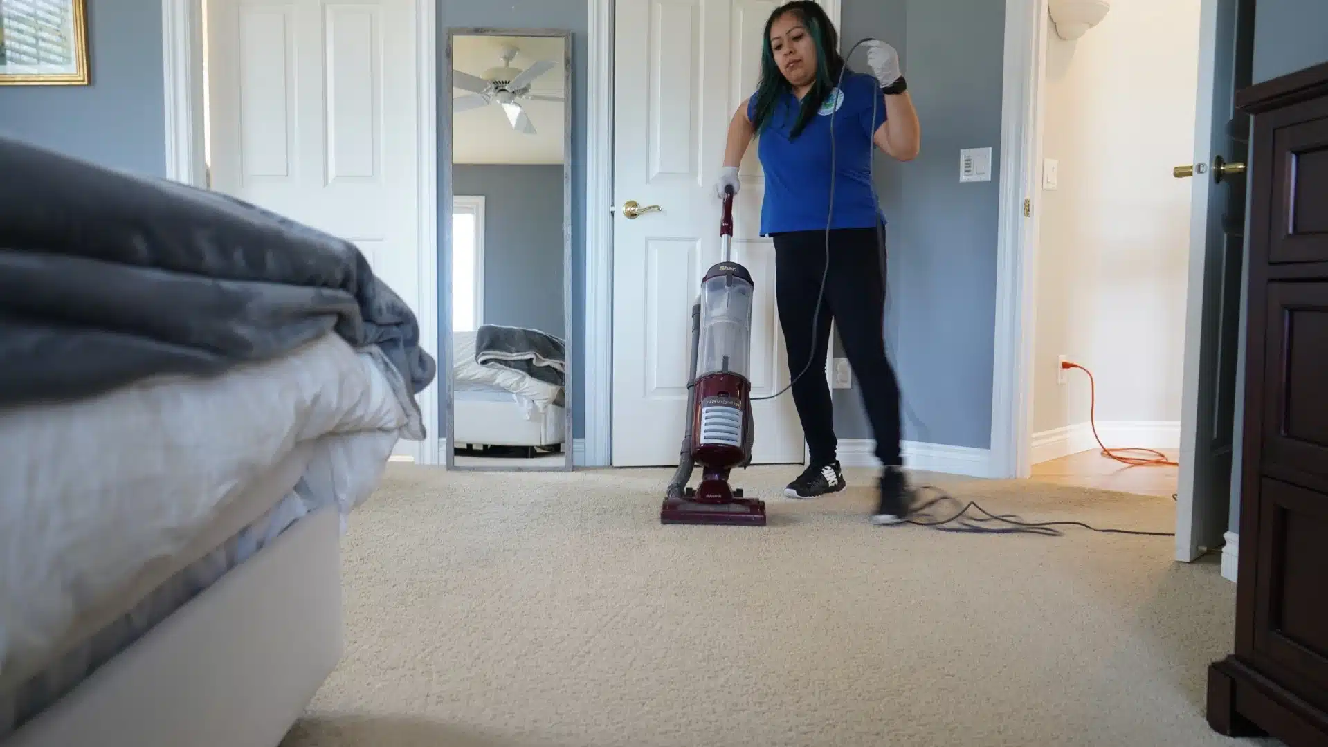 House cleaner vacuuming bedroom floor