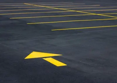 Yellow parking lot line striping and directional arrow on new asphalt