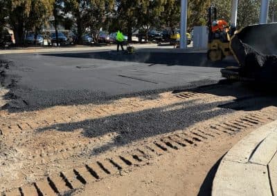 Asphalt paving crew resurfacing a gas station lot
