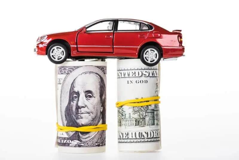 red model car sitting atop two rolls of cash