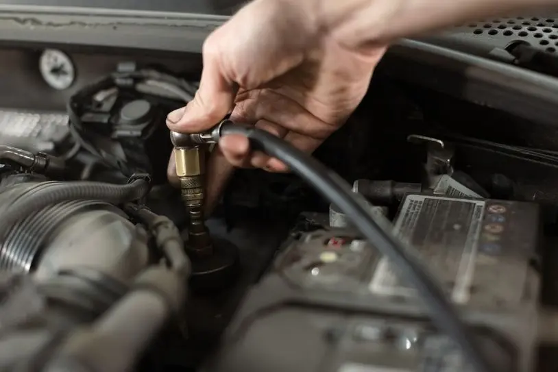 Male hands in repair shop holding the tank for changing car brake fluid.