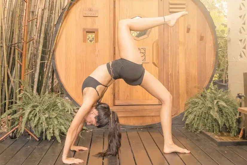 Woman practicing an advanced backbend during a stress relief yoga session at SILA Miami's outdoor jungle studio in Upper Buena Vista, FL