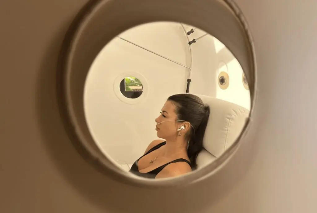 Woman relaxing inside the hyperbaric oxygen chamber during a recovery session at SILA Miami