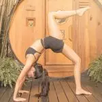 Woman practicing an advanced backbend during a stress relief yoga session at SILA Miami's outdoor jungle studio in Upper Buena Vista, FL