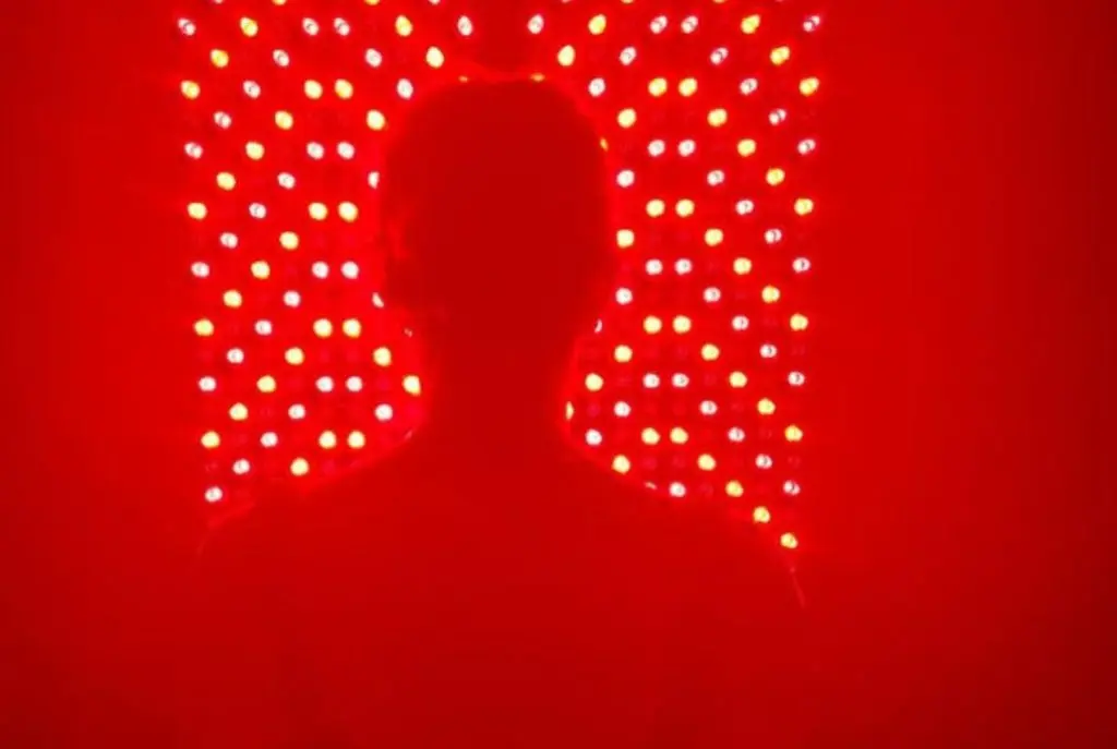 Full-body red light therapy session in Miami at SILA showing a client silhouette in front of a professional red and near-infrared light panel